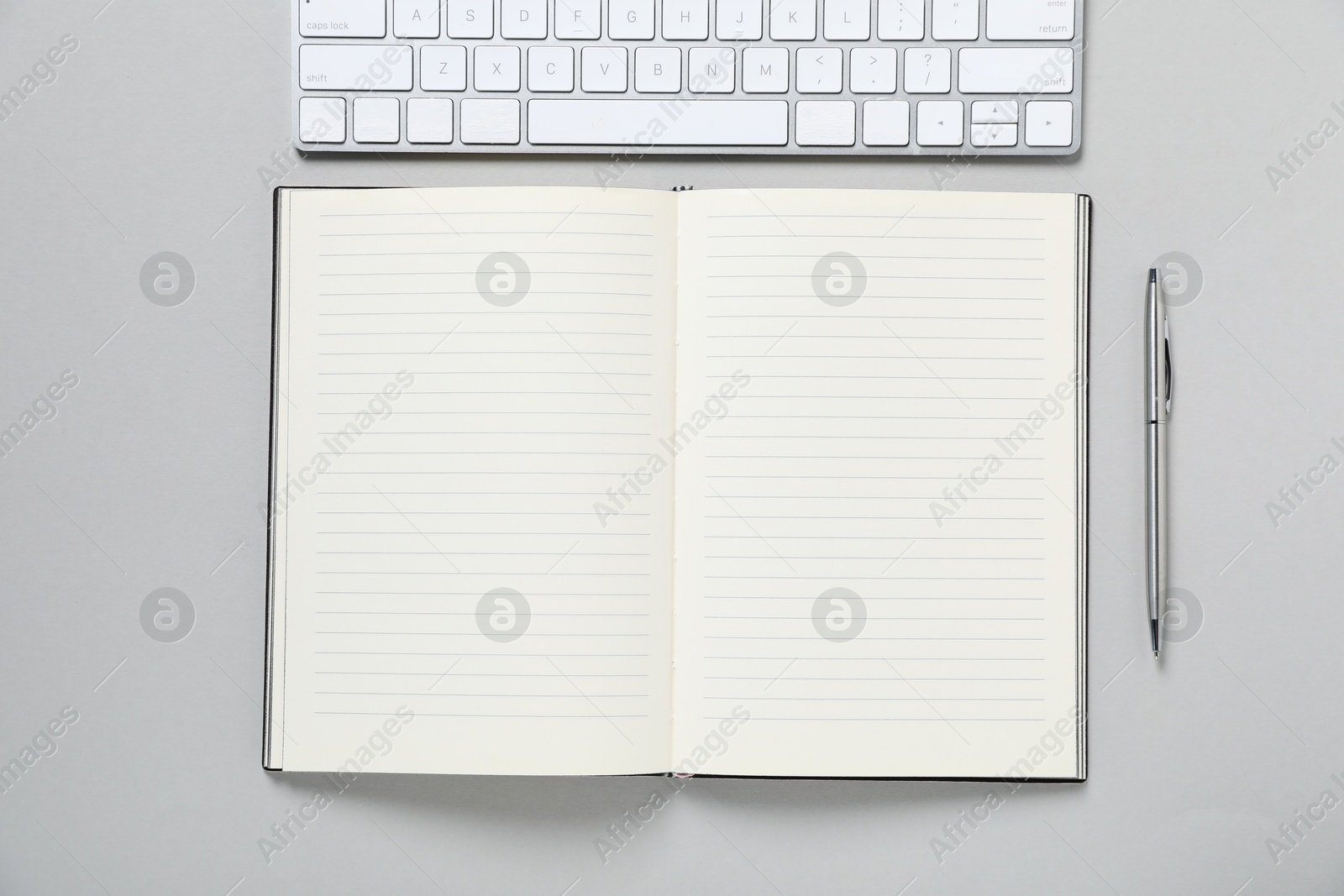 Open blank notebook, computer keyboard and pen on light grey background, flat lay Photo of Open blank notebook, computer keyboard and pen on light grey background, flat lay