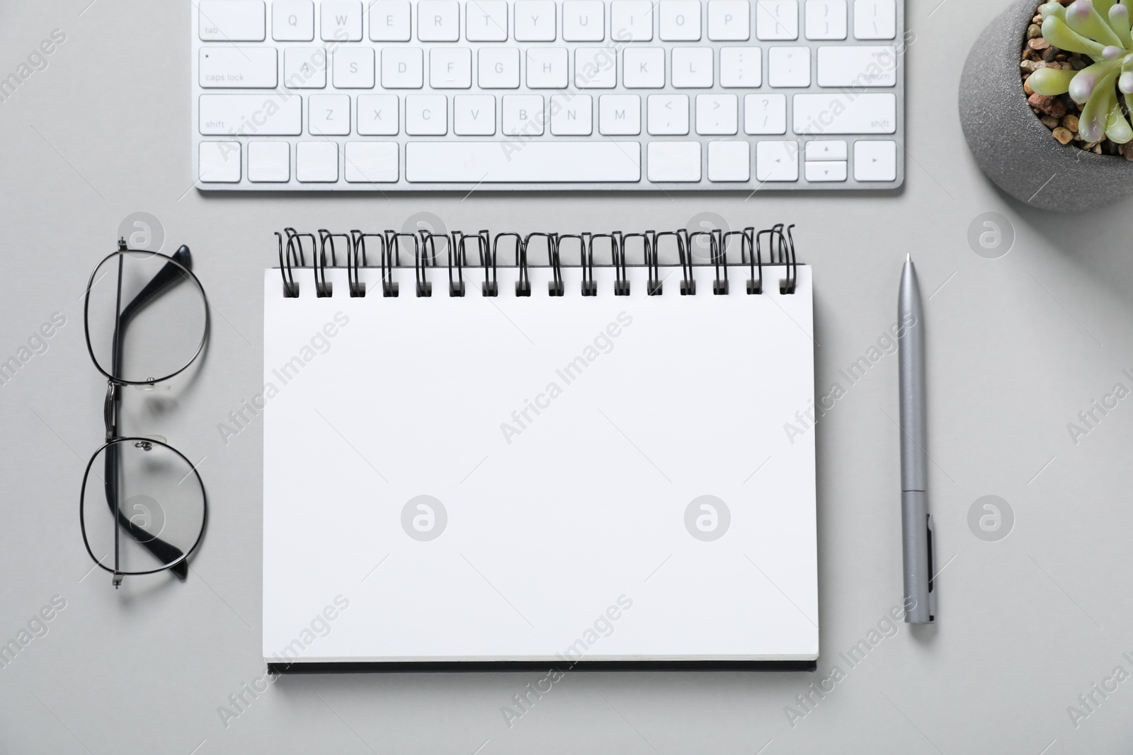 Open blank notebook, computer keyboard, glasses, pen and floral decor on light grey background, flat lay Photo of Open blank notebook, computer keyboard, glasses, pen and floral decor on light grey background, flat lay