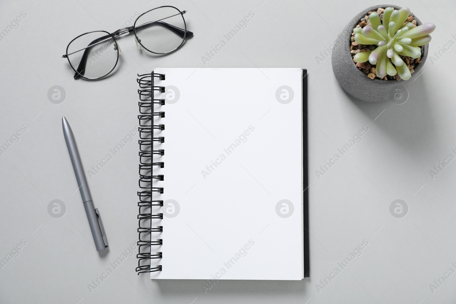 Open blank notebook, glasses, pen and floral decor on light grey background, flat lay Photo of Open blank notebook, glasses, pen and floral decor on light grey background, flat lay