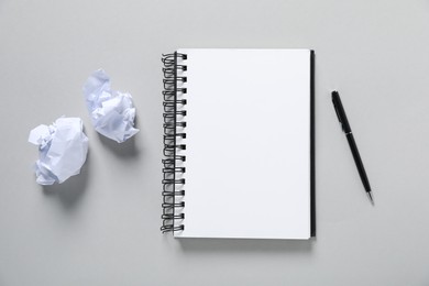 Photo of Open blank notebook, pen and crumpled paper on light grey background, flat lay