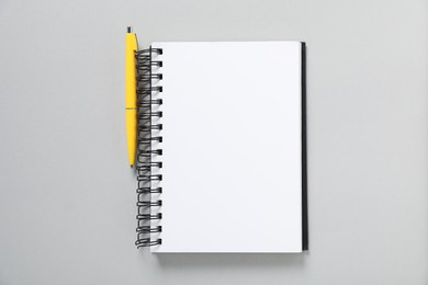 Photo of Open blank notebook and pen on light grey background, top view