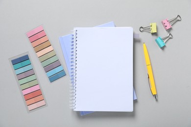 Photo of Open blank notebook and other stationery on light grey background, flat lay