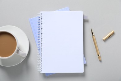 Photo of Open blank notebook, pen and coffee on light grey background, flat lay