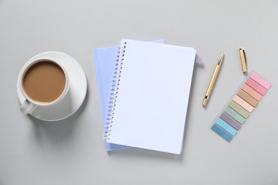Photo of Open blank notebook, colorful stickers, pen and coffee on light grey background, flat lay
