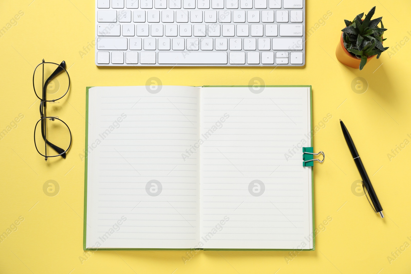 Open blank notebook, computer keyboard, glasses, pen and floral decor on yellow background, flat lay Photo of Open blank notebook, computer keyboard, glasses, pen and floral decor on yellow background, flat lay