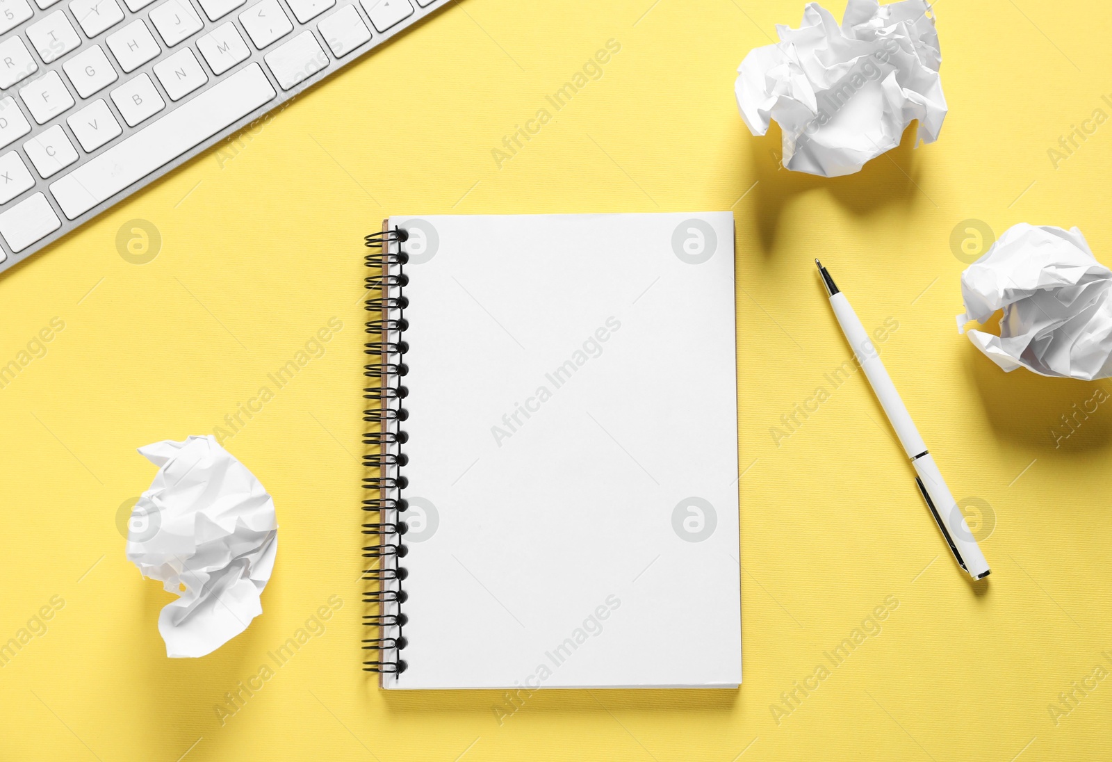 Open blank notebook, crumpled paper, pen and computer keyboard on yellow background, flat lay Photo of Open blank notebook, crumpled paper, pen and computer keyboard on yellow background, flat lay