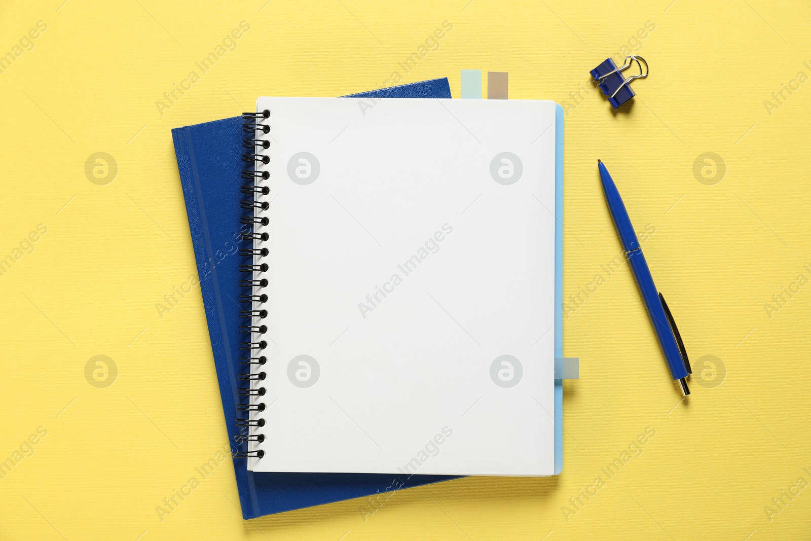 Open blank notebook and other stationery on yellow background, flat lay Photo of Open blank notebook and other stationery on yellow background, flat lay