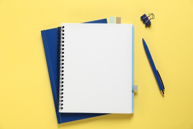Photo of Open blank notebook and other stationery on yellow background, flat lay