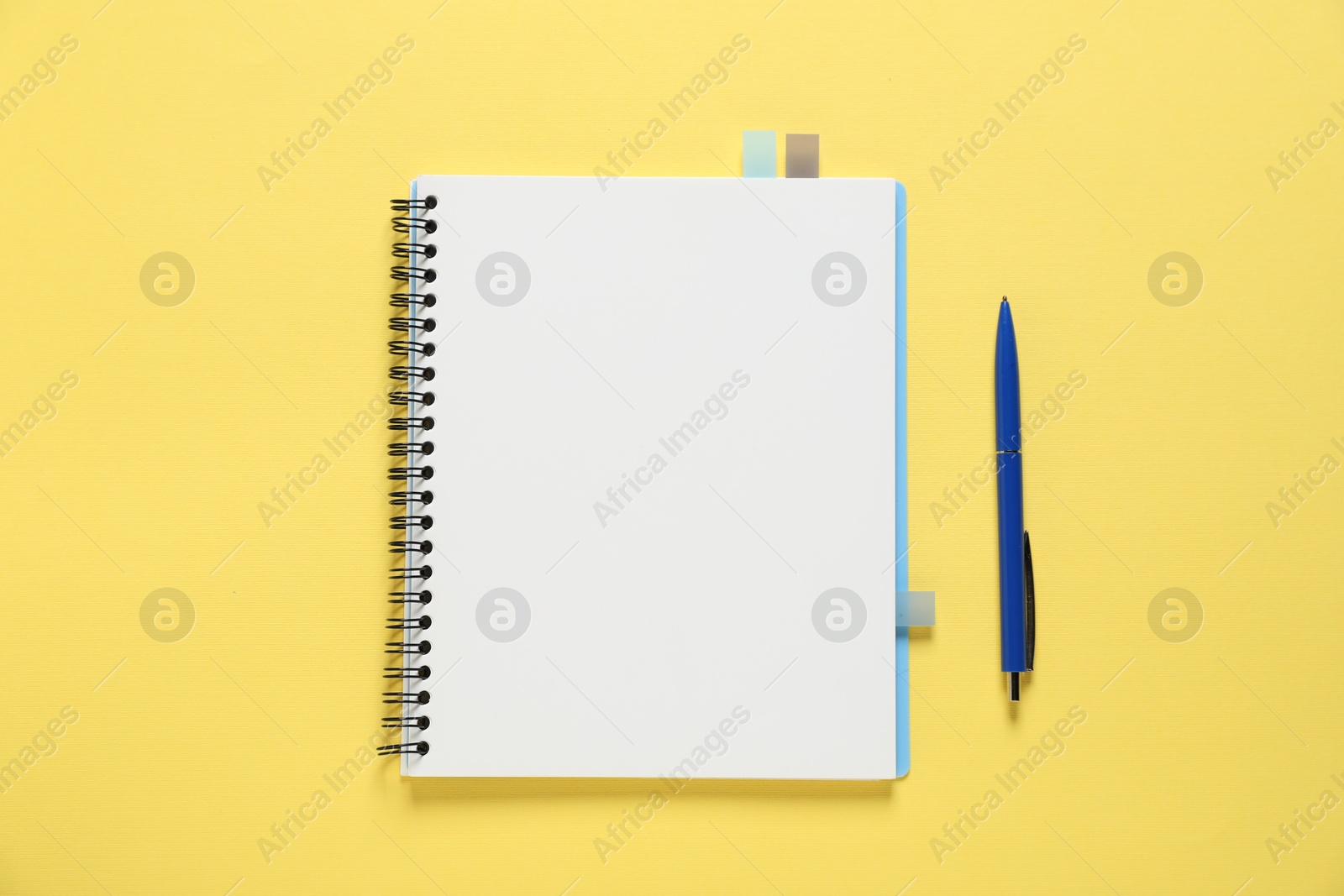 Open blank notebook and pen on yellow background, flat lay Photo of Open blank notebook and pen on yellow background, flat lay