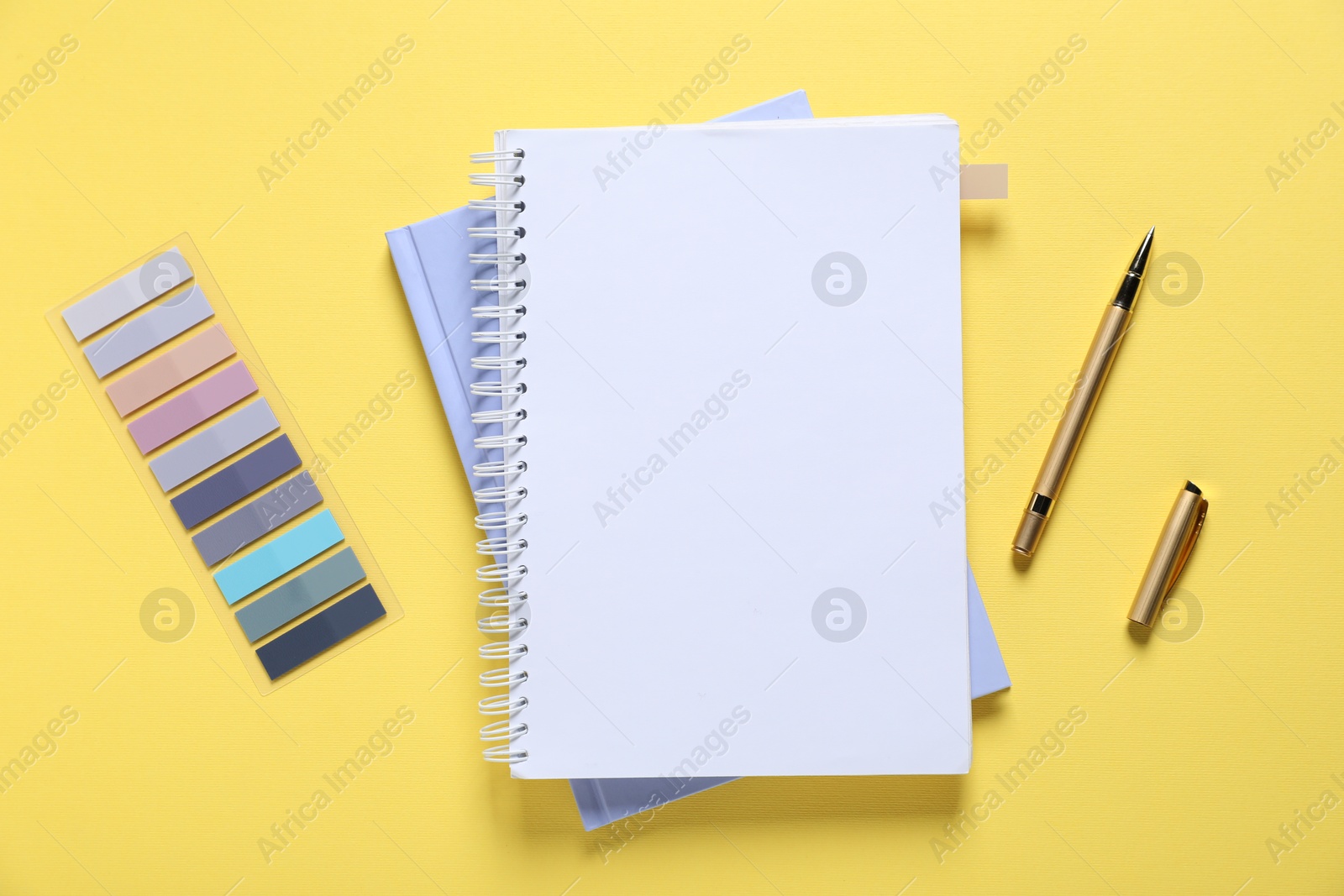 Open blank notebook and other stationery on yellow background, flat lay Photo of Open blank notebook and other stationery on yellow background, flat lay