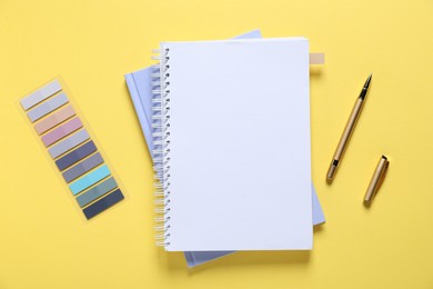 Photo of Open blank notebook and other stationery on yellow background, flat lay