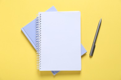 Photo of Open blank notebook and pen on yellow background, flat lay