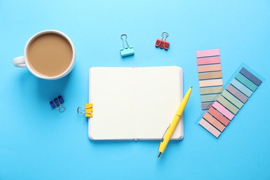 Photo of Open blank notebook, other stationery and coffee on light blue background, flat lay