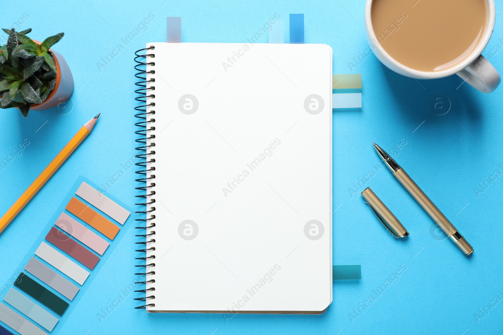 Open blank notebook, other stationery, coffee and floral decor on light blue background, flat lay Photo of Open blank notebook, other stationery, coffee and floral decor on light blue background, flat lay