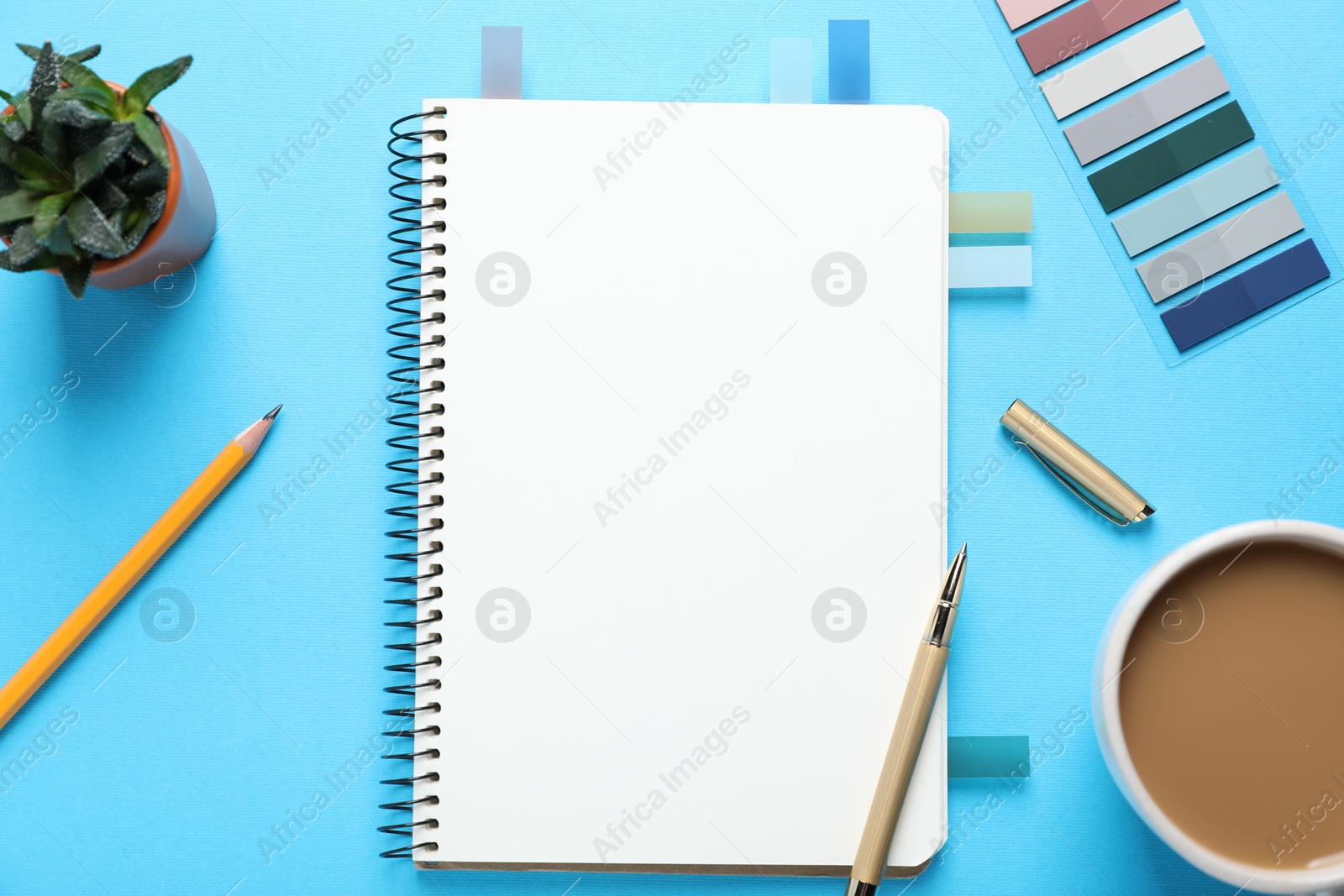 Open blank notebook, other stationery, coffee and floral decor on light blue background, flat lay Photo of Open blank notebook, other stationery, coffee and floral decor on light blue background, flat lay