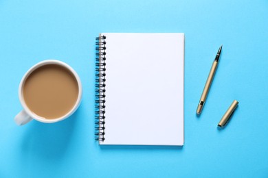 Photo of Open blank notebook, pen and coffee on light blue background, flat lay