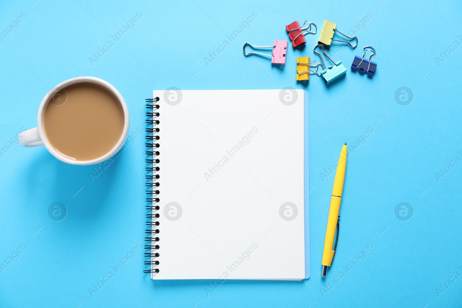 Open blank notebook, other stationery and coffee on light blue background, flat lay Photo of Open blank notebook, other stationery and coffee on light blue background, flat lay