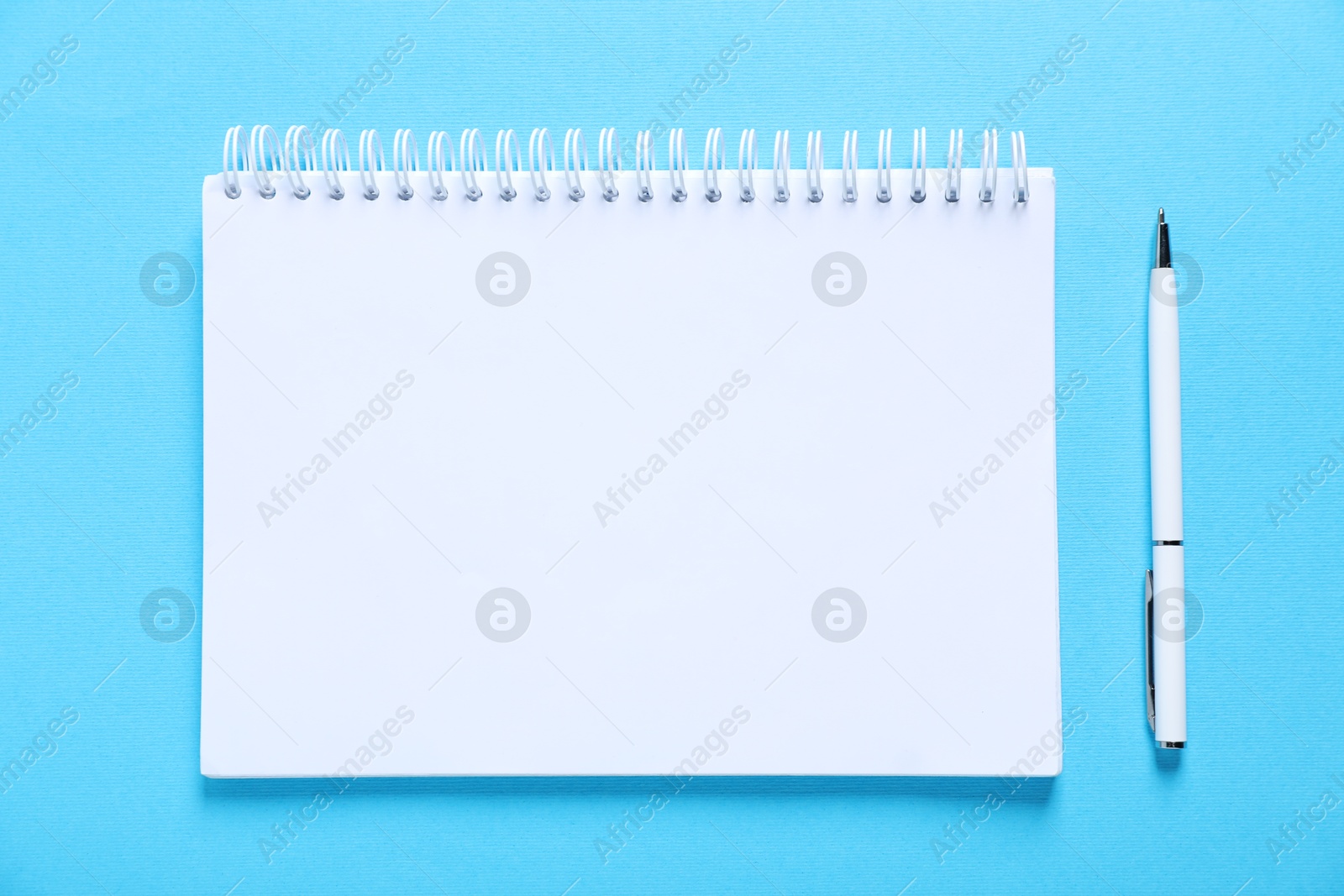 Open blank notebook and pen on light blue background, flat lay Photo of Open blank notebook and pen on light blue background, flat lay