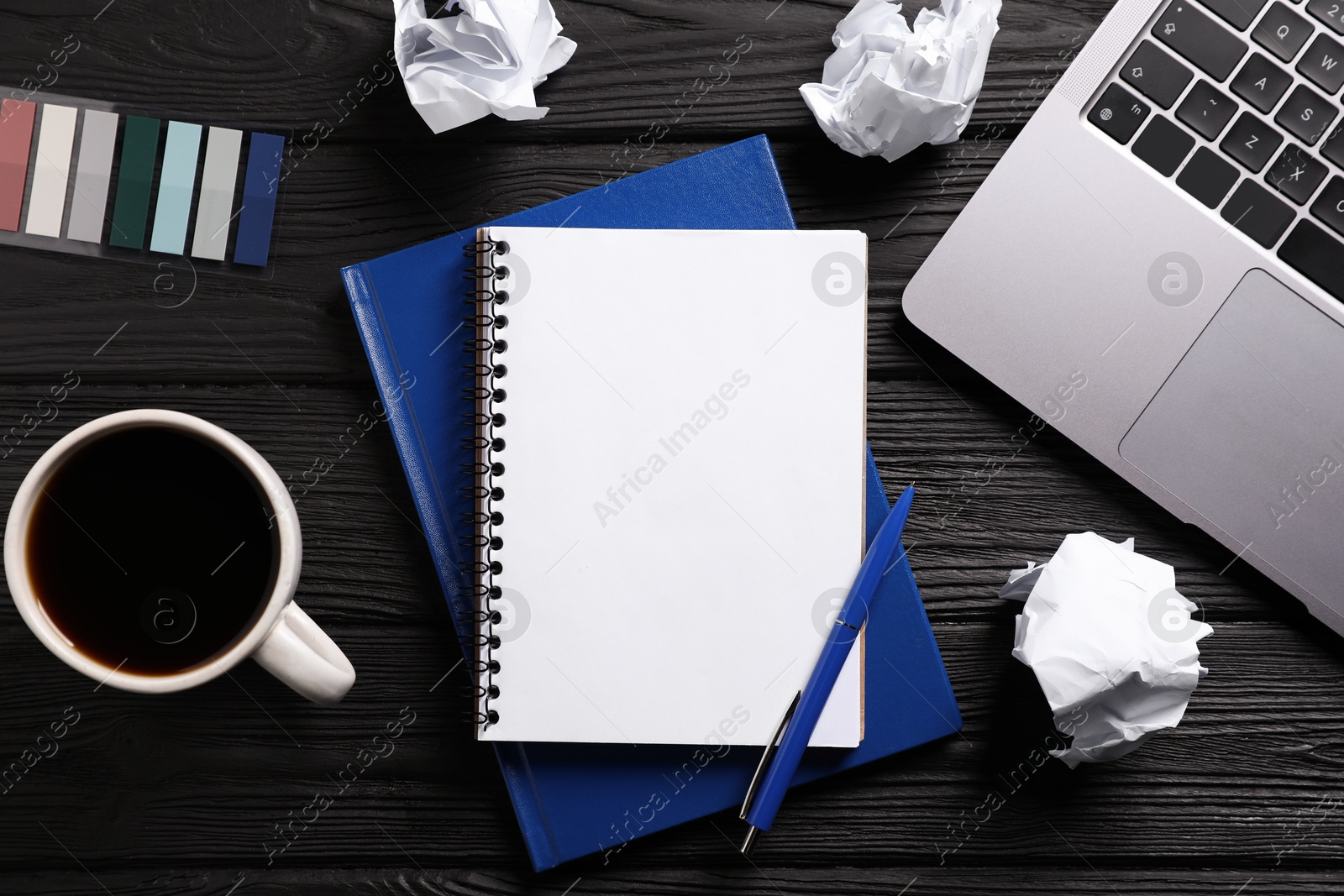 Open blank notebook, other stationery, coffee, crumpled paper and laptop on black wooden table, flat lay Photo of Open blank notebook, other stationery, coffee, crumpled paper and laptop on black wooden table, flat lay