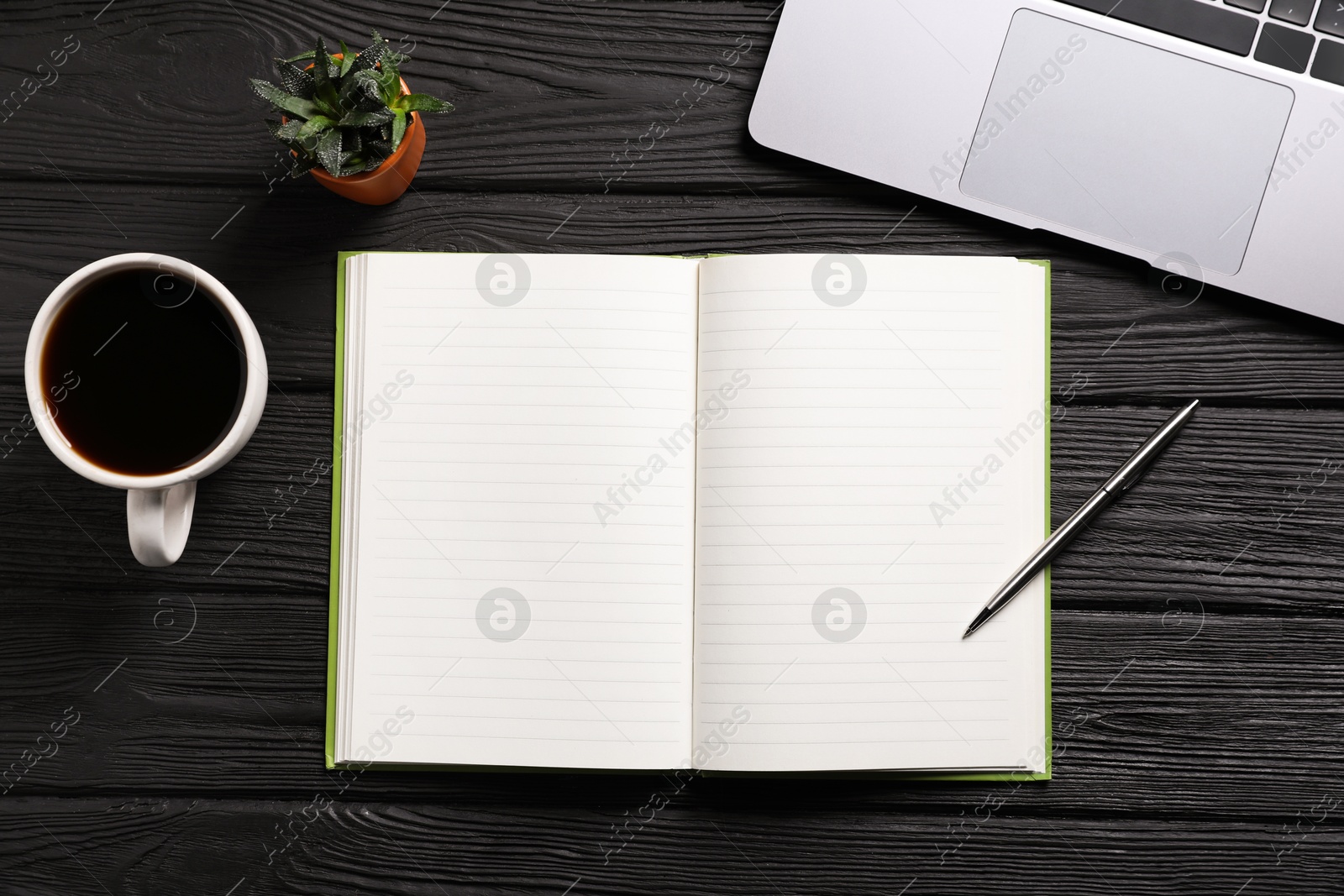 Open blank notebook, pen, coffee, laptop and floral decor on black wooden table, flat lay Photo of Open blank notebook, pen, coffee, laptop and floral decor on black wooden table, flat lay