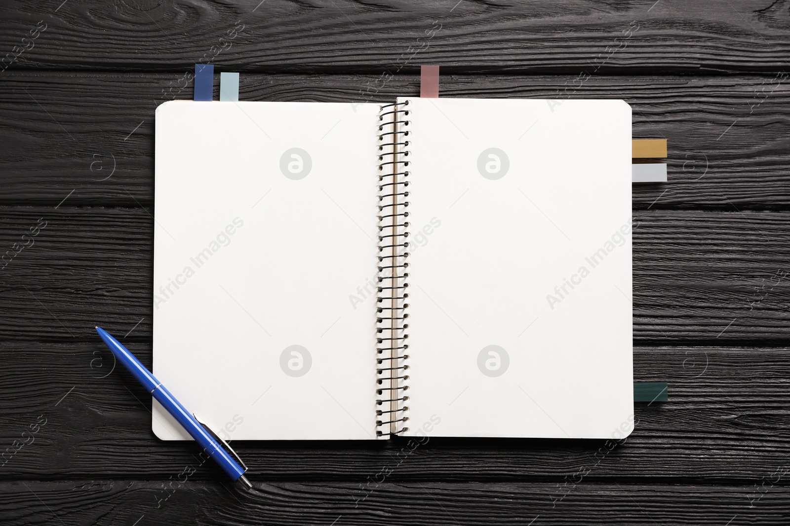 Open blank notebook with colorful stickers and pen on black wooden table, top view Photo of Open blank notebook with colorful stickers and pen on black wooden table, top view