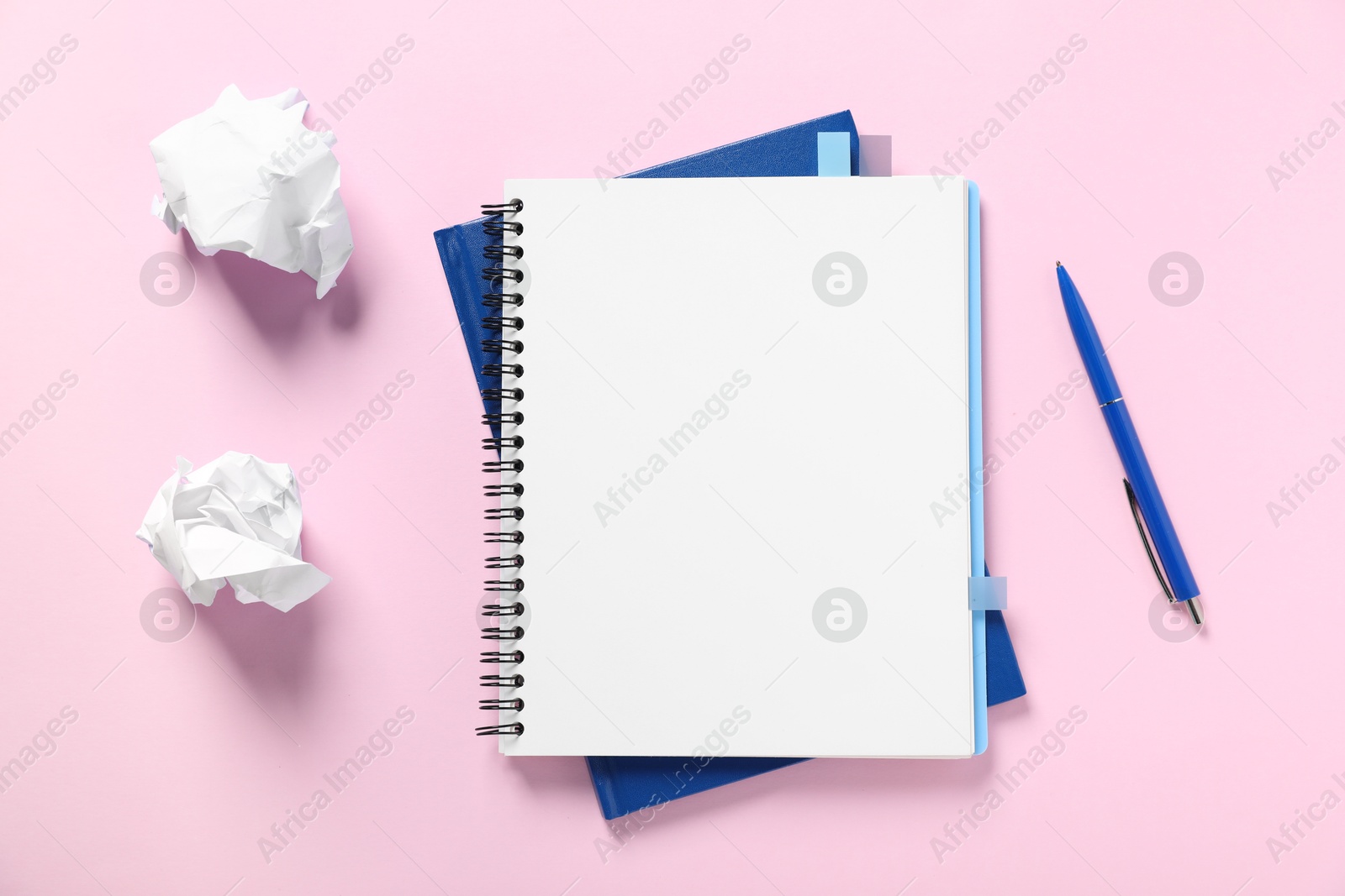 Open blank notebook, crumpled paper and pen on pink background, flat lay Photo of Open blank notebook, crumpled paper and pen on pink background, flat lay