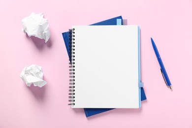 Photo of Open blank notebook, crumpled paper and pen on pink background, flat lay