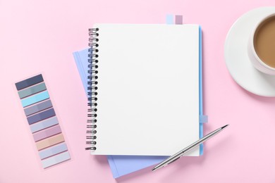Photo of Open blank notebook, colorful stickers, pen and coffee on pink background, flat lay