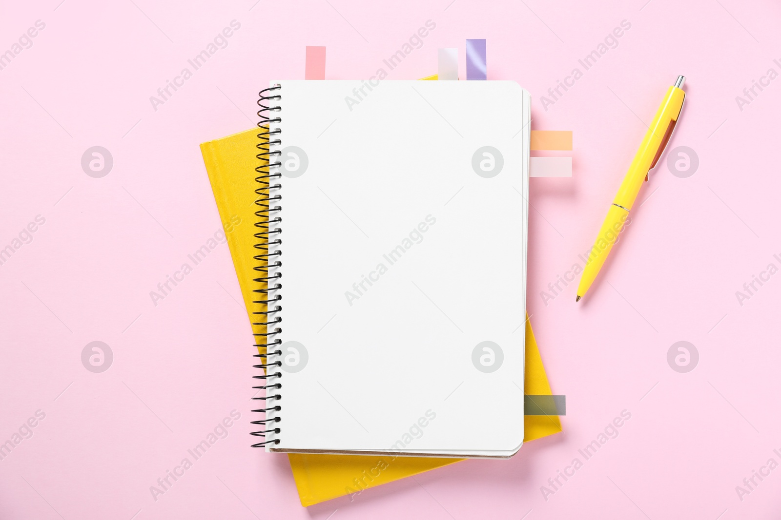 Open blank notebook with colorful stickers and pen on pink background, flat lay Photo of Open blank notebook with colorful stickers and pen on pink background, flat lay