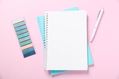Photo of Open blank notebook, colorful stickers and pen on pink background, flat lay