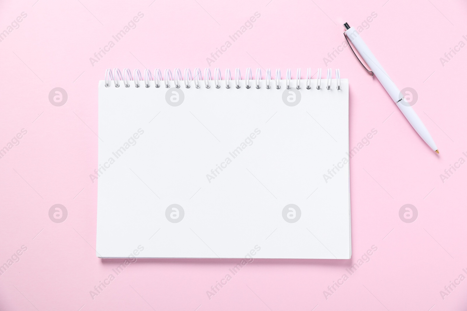Open blank notebook and pen on pink background, flat lay Photo of Open blank notebook and pen on pink background, flat lay