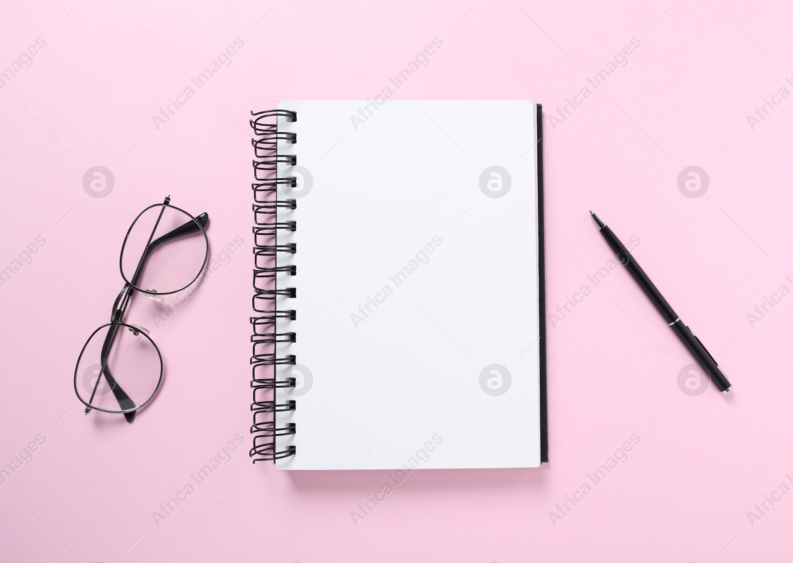 Open blank notebook, glasses and pen on pink background, flat lay Photo of Open blank notebook, glasses and pen on pink background, flat lay
