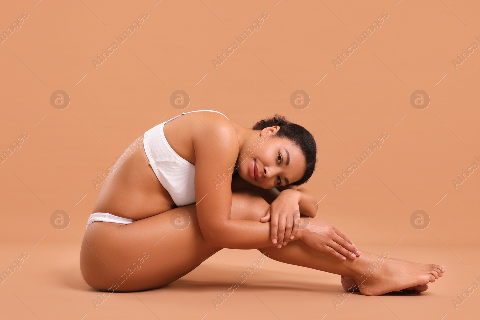 Woman in white underwear with smooth skin after epilation procedure on beige background Photo of Woman in white underwear with smooth skin after epilation procedure on beige background