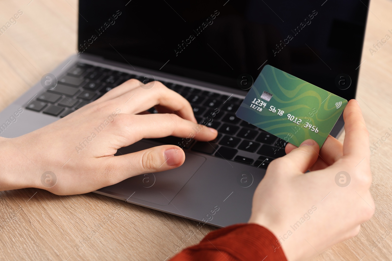 Online payment. Woman with credit card typing on laptop at wooden table, closeup Photo of Online payment. Woman with credit card typing on laptop at wooden table, closeup