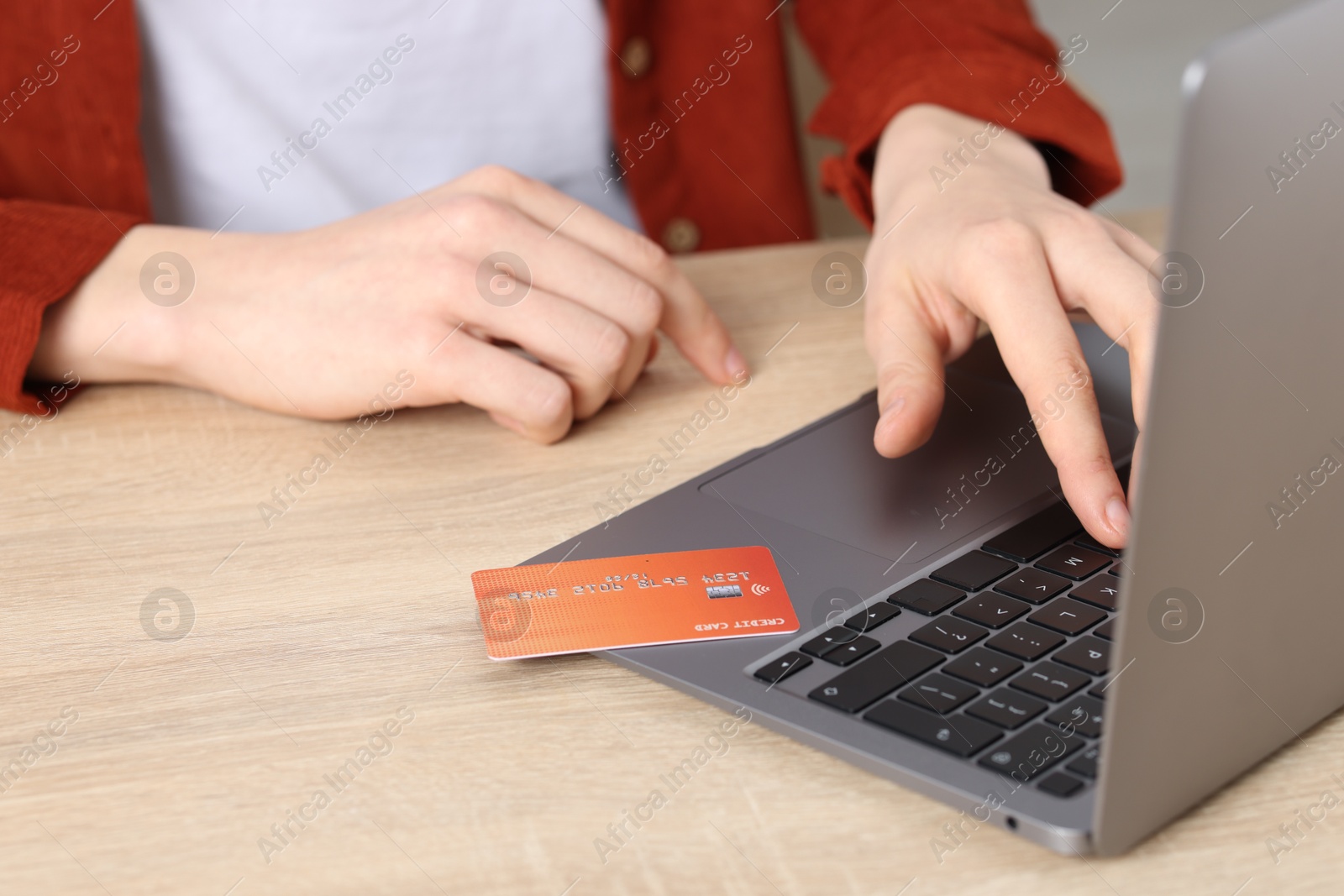 Online payment. Woman with credit card typing on laptop at wooden table, closeup Photo of Online payment. Woman with credit card typing on laptop at wooden table, closeup
