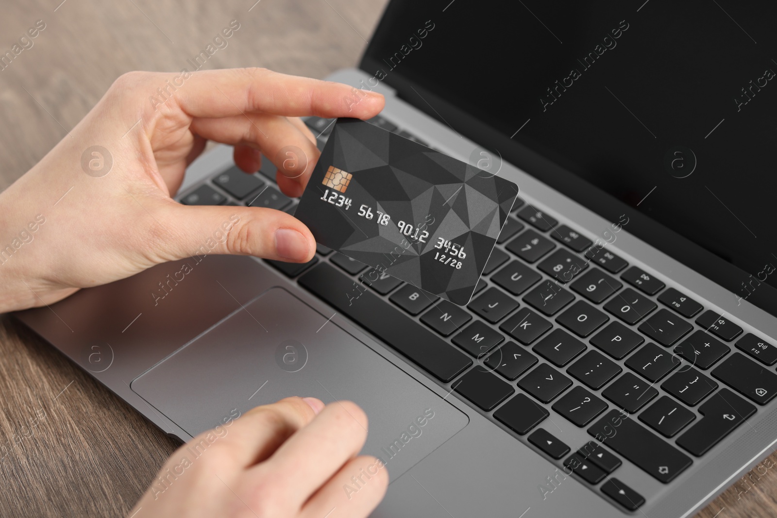 Photo of Online payment. Woman with credit card using laptop at wooden table, closeup