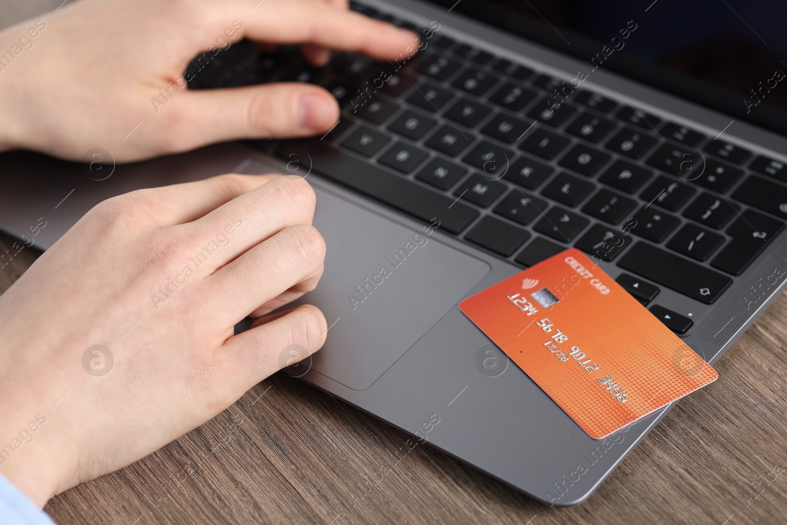 Online payment. Woman with credit card typing on laptop at wooden table, closeup Photo of Online payment. Woman with credit card typing on laptop at wooden table, closeup