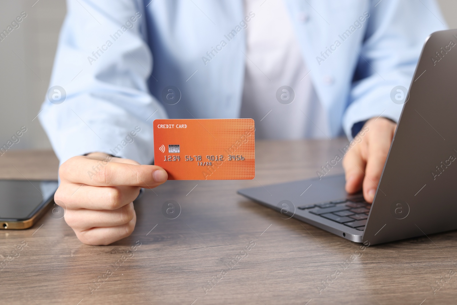 Online payment. Woman with credit card and laptop at wooden table, closeup Photo of Online payment. Woman with credit card and laptop at wooden table, closeup
