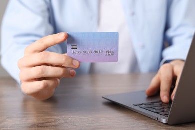 Photo of Online payment. Woman with credit card and laptop at wooden table, closeup