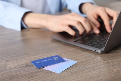 Photo of Online payment. Woman typing on laptop at wooden table, focus on credit cards