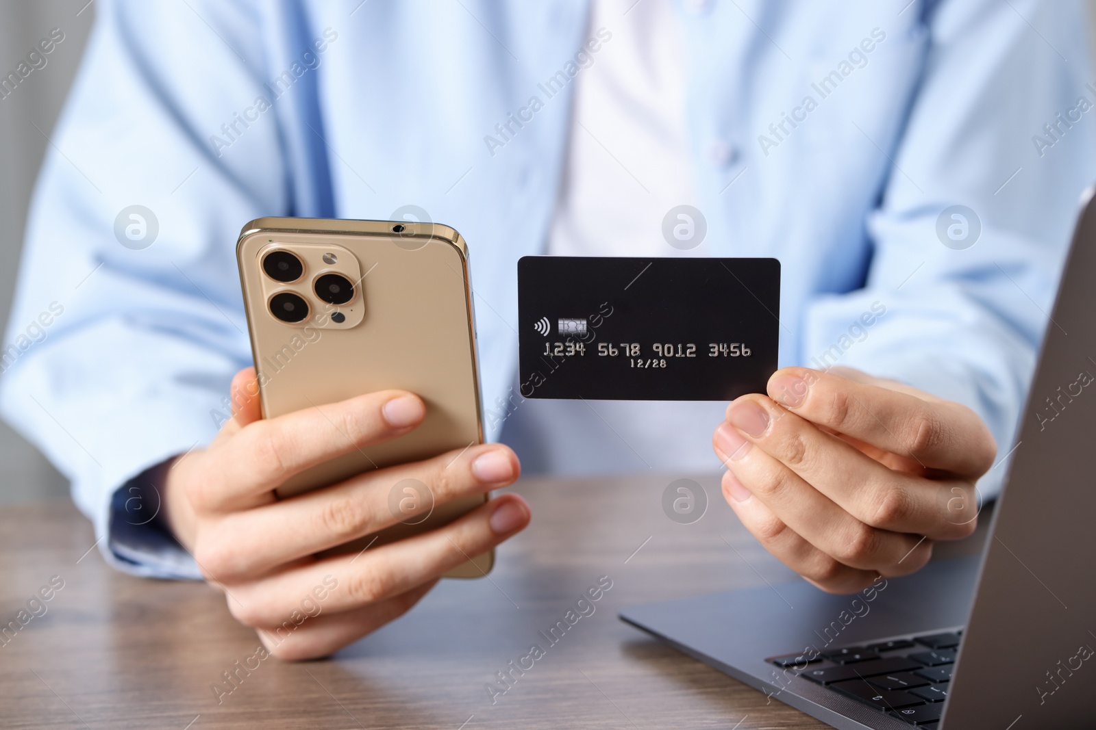 Woman with credit card, smartphone and laptop paying online at wooden table, closeup Photo of Woman with credit card, smartphone and laptop paying online at wooden table, closeup