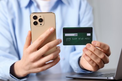 Photo of Woman with credit card, smartphone and laptop paying online at table, closeup