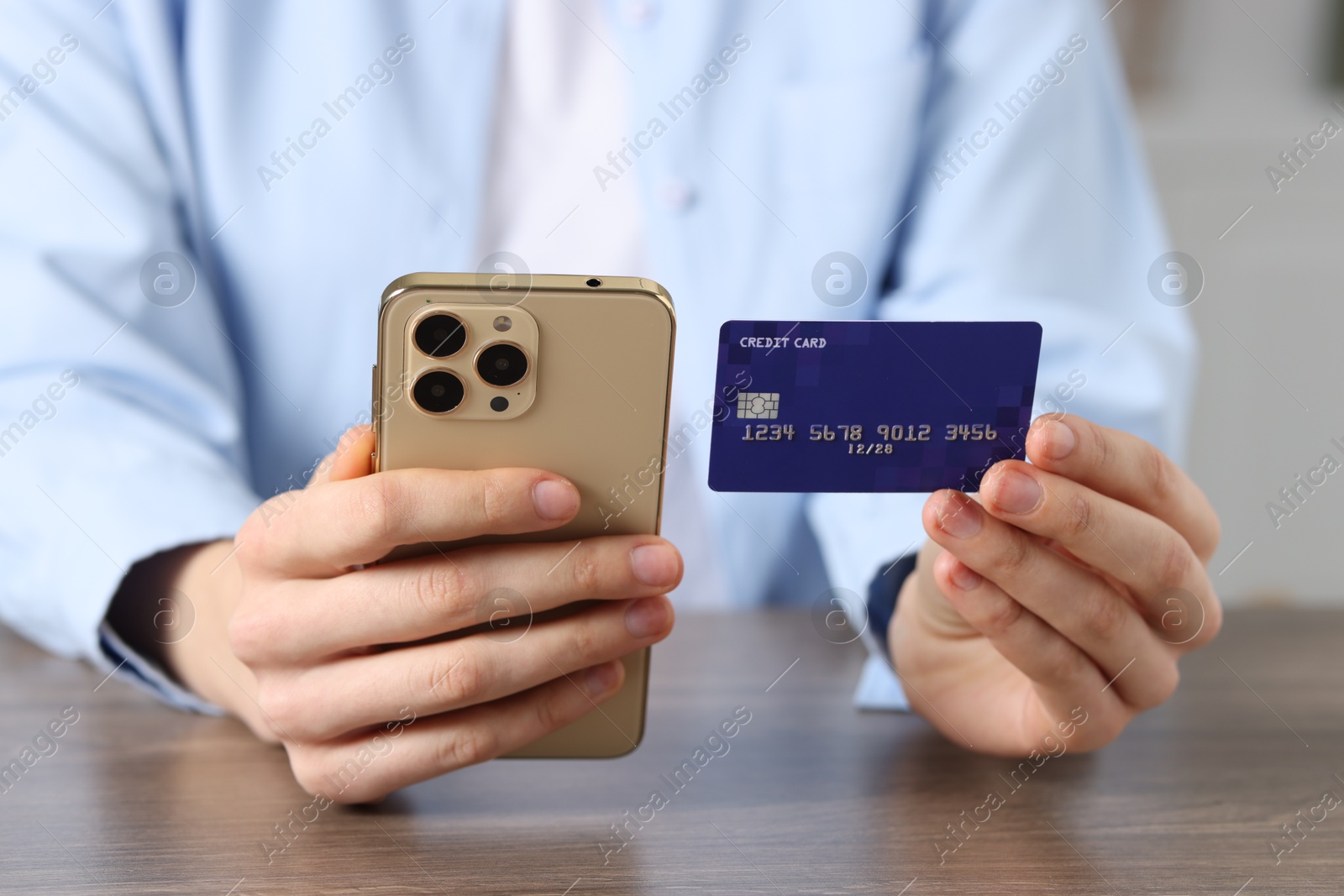 Woman with credit card and smartphone paying online at wooden table, closeup Photo of Woman with credit card and smartphone paying online at wooden table, closeup