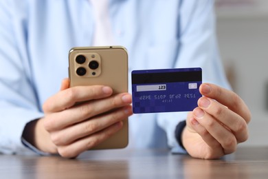 Photo of Woman with credit card and smartphone paying online at table, selective focus