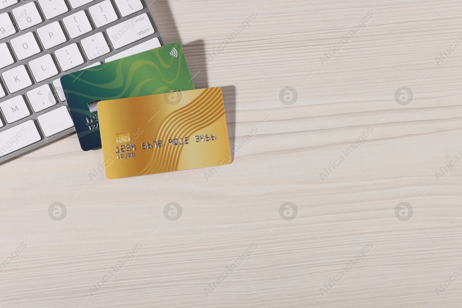 Online payment. Credit cards and computer keyboard on light wooden table, top view. Space for text Photo of Online payment. Credit cards and computer keyboard on light wooden table, top view. Space for text