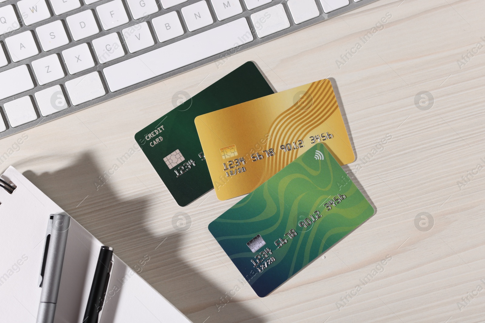 Photo of Online payment. Credit cards, stationery and computer keyboard on light wooden table, flat lay