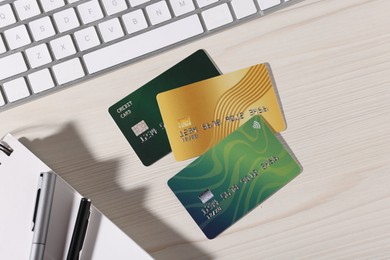 Photo of Online payment. Credit cards, stationery and computer keyboard on light wooden table, flat lay