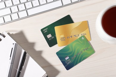 Photo of Online payment. Credit cards, stationery and computer keyboard on light wooden table, flat lay