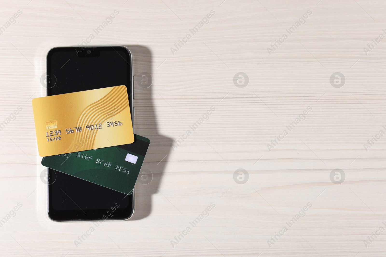 Photo of Online payment. Credit cards and smartphone on light wooden table, top view. Space for text