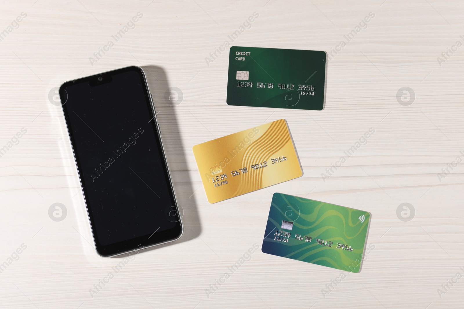 Photo of Online payment. Credit cards and smartphone on light wooden table, flat lay